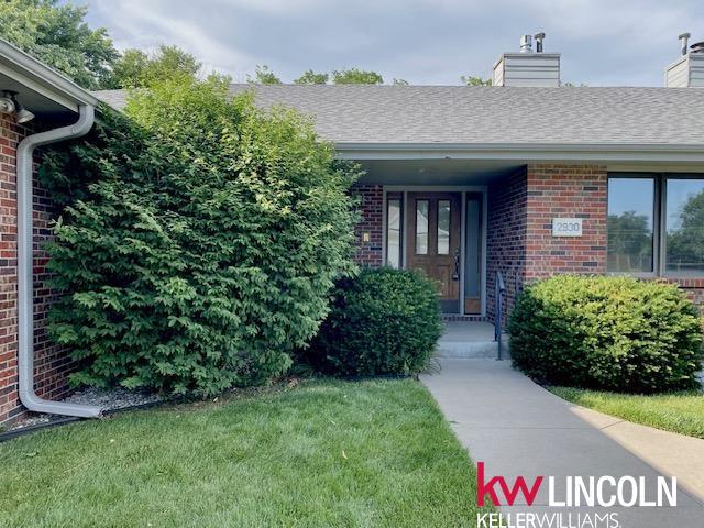 2930 Drawbridge Ct, Lincoln, NE 68516 - property entrance with brick siding, a lawn, and a chimney