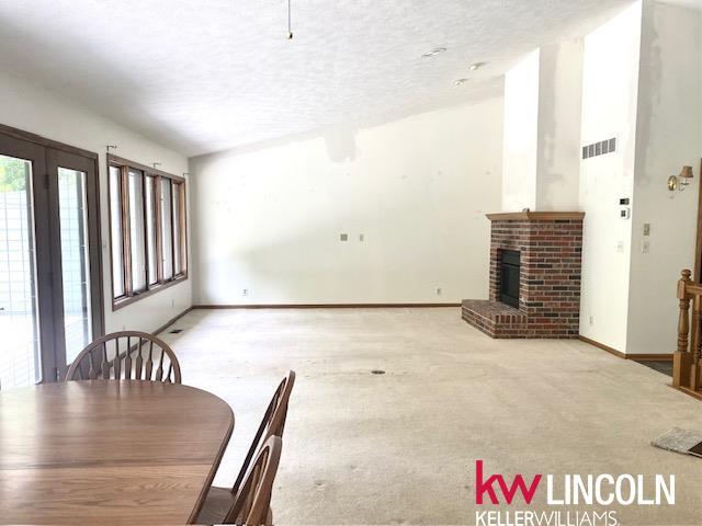 2930 Drawbridge Ct, Lincoln, NE 68516 - dining room featuring a brick fireplace, a textured ceiling, and carpet