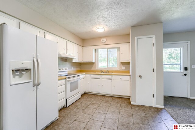2811 S 36th St, Omaha, NE 68105 - kitchen with white appliances, under cabinet range hood, light countertops, white cabinetry, and a textured ceiling