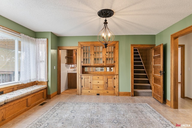 210 W Moravia Ave, Prague, NE 68050 - dining space with light tile patterned floors, stairway, a textured ceiling, and a chandelier