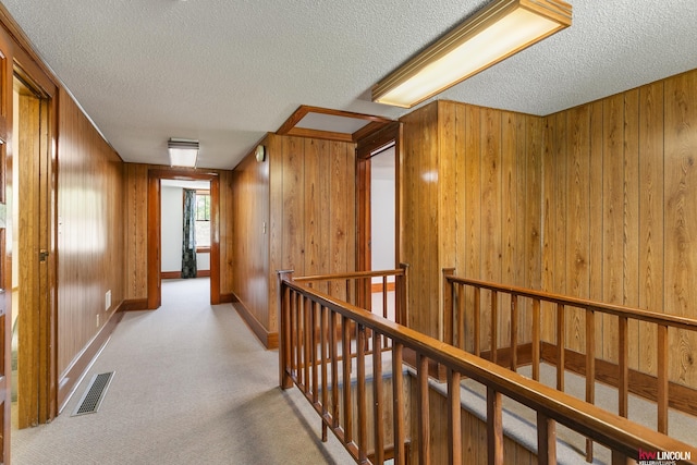 210 W Moravia Ave, Prague, NE 68050 - hallway featuring an upstairs landing, wood walls, a textured ceiling, and carpet floors