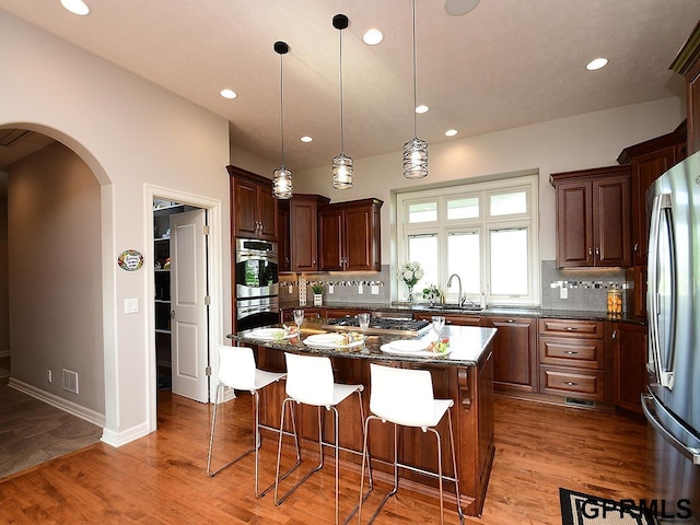 1526 Provencal Cir, Yutan, NE 68073 - kitchen with stainless steel appliances, arched walkways, recessed lighting, backsplash, and a breakfast bar