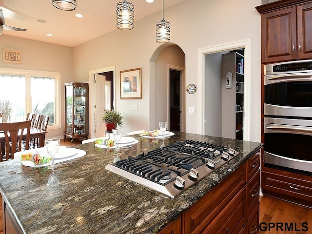 1526 Provencal Cir, Yutan, NE 68073 - kitchen with stainless steel appliances, arched walkways, dark wood finished floors, dark stone countertops, and recessed lighting