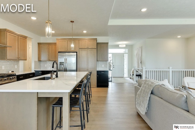 12386 Fenwick St, Papillion, NE 68046 - kitchen with stainless steel appliances, backsplash, light wood finished floors, a breakfast bar, and open floor plan