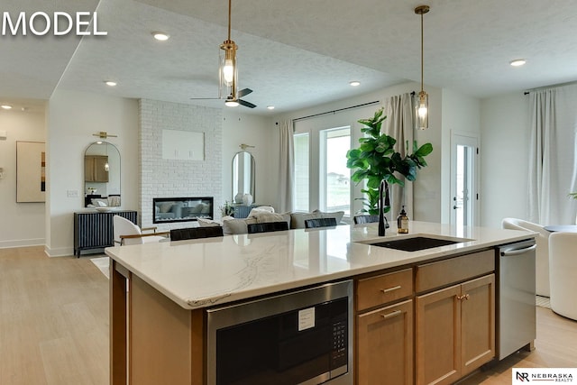 12386 Fenwick St, Papillion, NE 68046 - kitchen with stainless steel appliances, light wood-type flooring, a center island with sink, ceiling fan, and hanging light fixtures