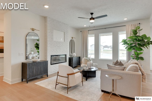 12386 Fenwick St, Papillion, NE 68046 - living area with light wood-style floors, a ceiling fan, a brick fireplace, recessed lighting, and a textured ceiling