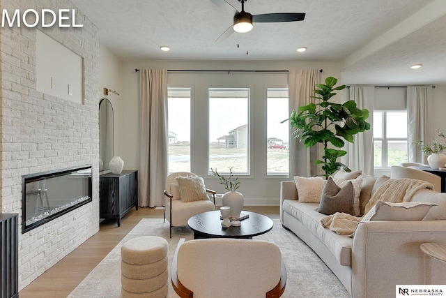 12386 Fenwick St, Papillion, NE 68046 - living room featuring light wood-style floors, ceiling fan, a fireplace, and a textured ceiling