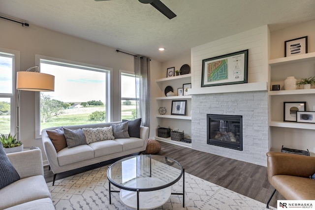 19015 Ranch Dr, Papillion, NE 68046 - living room with a ceiling fan, built in shelves, light wood-type flooring, a textured ceiling, and a fireplace