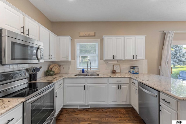 16454 Drexel St, Omaha, NE 68135 - kitchen with appliances with stainless steel finishes, dark wood-style flooring, a peninsula, decorative backsplash, and white cabinets