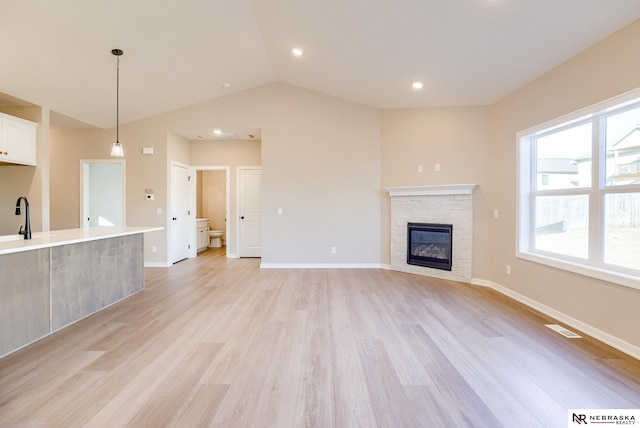 11152 Portage Dr, Papillion, NE 68046 - unfurnished living room with light wood-style floors, a stone fireplace, vaulted ceiling, and recessed lighting