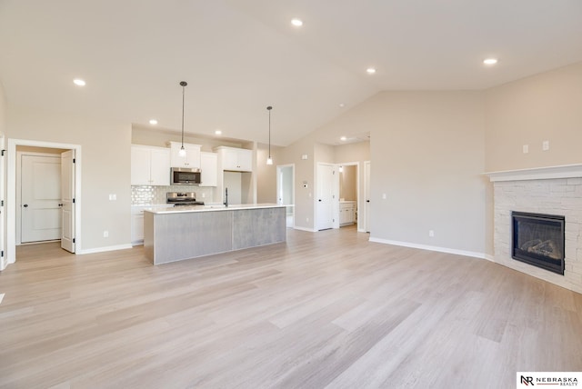 11152 Portage Dr, Papillion, NE 68046 - unfurnished living room featuring lofted ceiling, recessed lighting, light wood-style flooring, and a fireplace