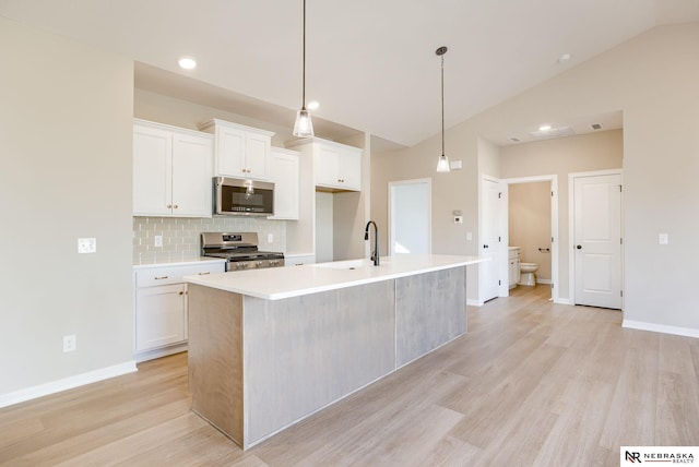 11152 Portage Dr, Papillion, NE 68046 - kitchen with stainless steel appliances, lofted ceiling, light wood finished floors, a center island with sink, and white cabinetry