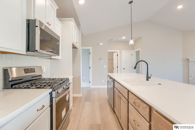 11152 Portage Dr, Papillion, NE 68046 - kitchen with appliances with stainless steel finishes, light wood-type flooring, backsplash, vaulted ceiling, and hanging light fixtures