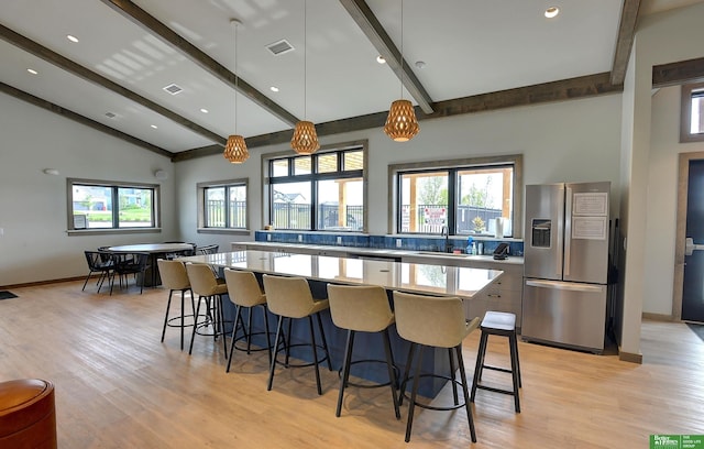 4802 N 187th Ave, Elkhorn, NE 68022 - kitchen featuring appliances with stainless steel finishes, a kitchen island, beamed ceiling, a breakfast bar area, and healthy amount of natural light