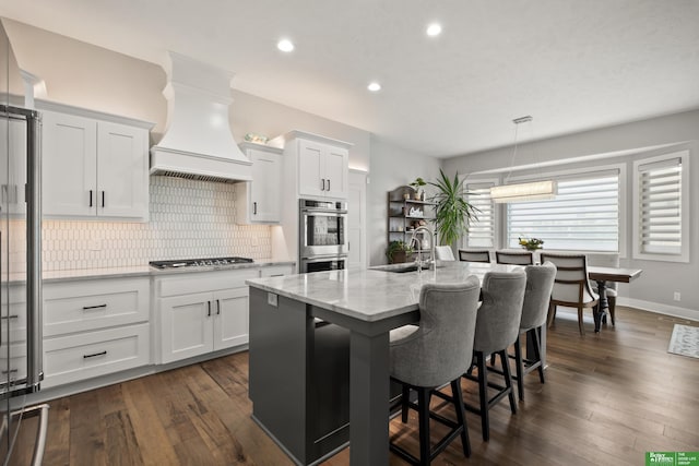 4802 N 187th Ave, Elkhorn, NE 68022 - kitchen with premium range hood, appliances with stainless steel finishes, backsplash, a kitchen island with sink, and white cabinetry