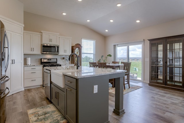12618 Glenn St, Omaha, NE 68138 - kitchen featuring stainless steel appliances, lofted ceiling, wood finished floors, a breakfast bar, and a kitchen island with sink
