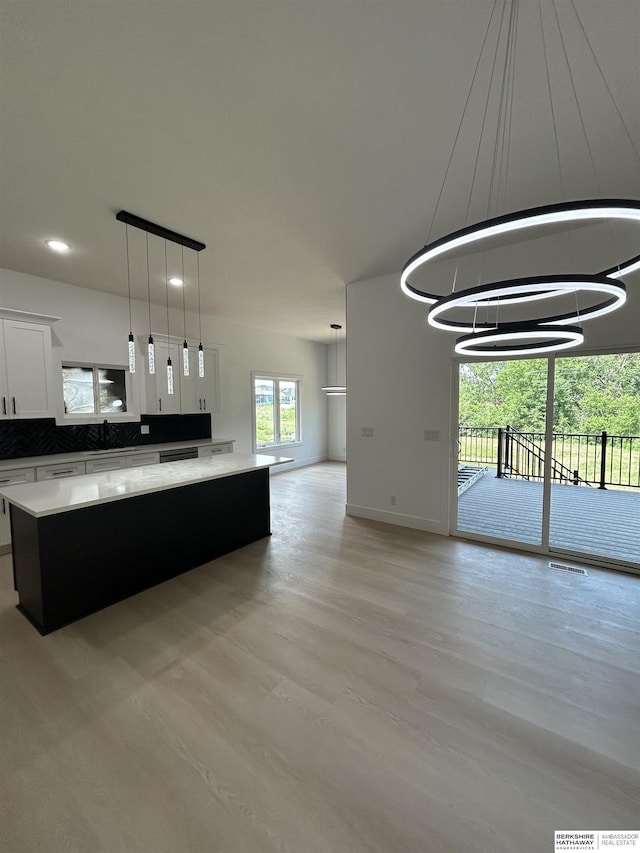 19756 Briar St, Gretna, NE 68028 - kitchen featuring a kitchen island, light countertops, white cabinets, light wood-style floors, and decorative light fixtures