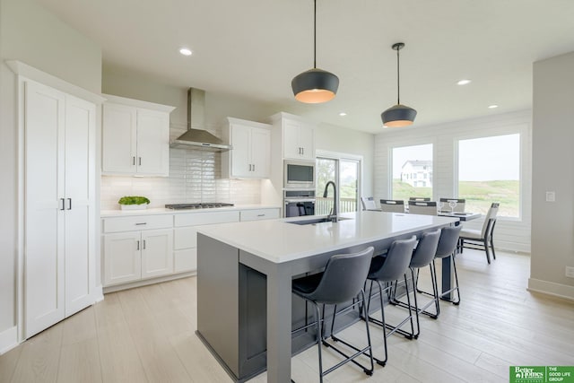 10110 Laramie St, Papillion, NE 68046 - kitchen with wall chimney exhaust hood, appliances with stainless steel finishes, backsplash, a center island with sink, and light countertops