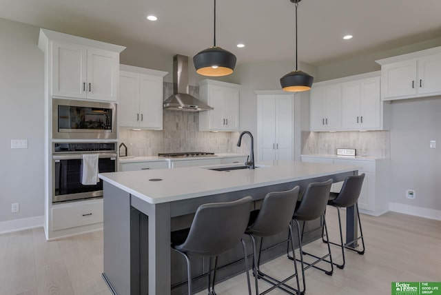 5602 N 212th St, Elkhorn, NE 68022 - kitchen featuring appliances with stainless steel finishes, wall chimney exhaust hood, tasteful backsplash, a center island with sink, and recessed lighting