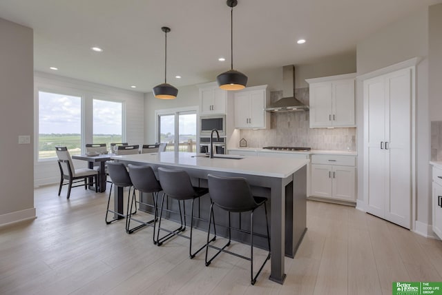5602 N 212th St, Elkhorn, NE 68022 - kitchen featuring wall chimney exhaust hood, a kitchen bar, a center island with sink, backsplash, and light countertops