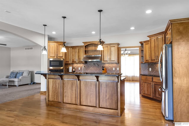 10149 Edward St, La Vista, NE 68128 - kitchen with under cabinet range hood, stainless steel appliances, open floor plan, arched walkways, and a breakfast bar