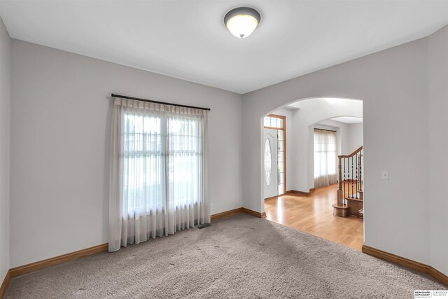 10149 Edward St, La Vista, NE 68128 - empty room with light colored carpet, arched walkways, healthy amount of natural light, and stairs