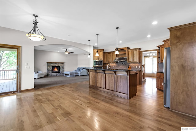 10149 Edward St, La Vista, NE 68128 - kitchen with open floor plan, appliances with stainless steel finishes, under cabinet range hood, a fireplace, and dark countertops