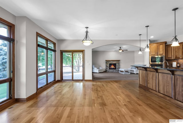 10149 Edward St, La Vista, NE 68128 - kitchen featuring stainless steel microwave, open floor plan, a stone fireplace, brown cabinets, and dark countertops