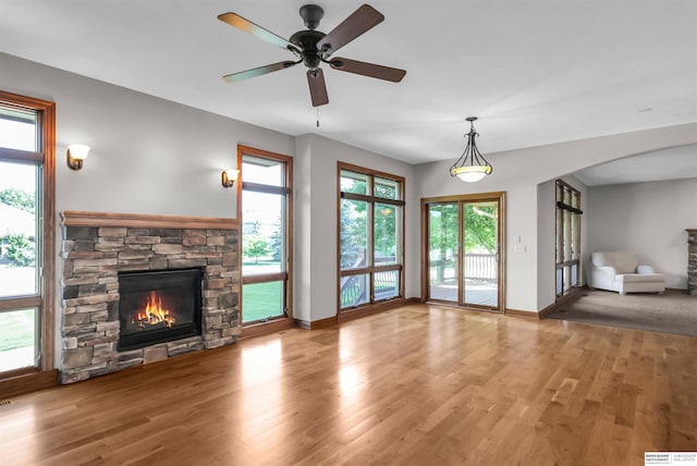10149 Edward St, La Vista, NE 68128 - unfurnished living room featuring a fireplace, arched walkways, wood finished floors, and a ceiling fan