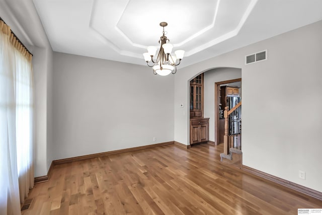10149 Edward St, La Vista, NE 68128 - unfurnished room featuring a chandelier, arched walkways, a tray ceiling, and light wood finished floors