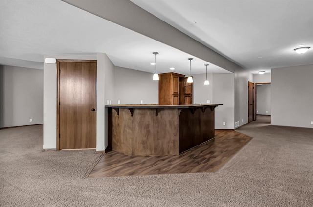 10149 Edward St, La Vista, NE 68128 - kitchen with dark carpet, brown cabinetry, a kitchen bar, hanging light fixtures, and a peninsula