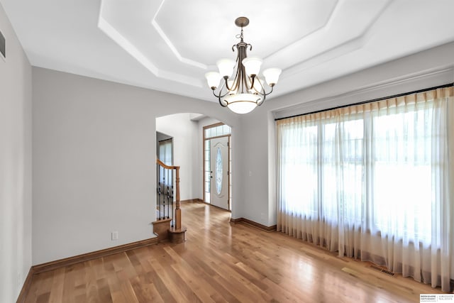 10149 Edward St, La Vista, NE 68128 - unfurnished room featuring arched walkways, a raised ceiling, a chandelier, wood finished floors, and stairway