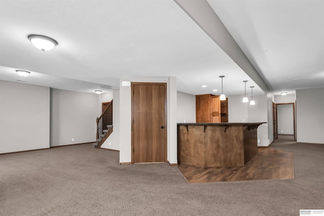 10149 Edward St, La Vista, NE 68128 - kitchen featuring brown cabinetry, carpet flooring, a peninsula, dark countertops, and decorative light fixtures