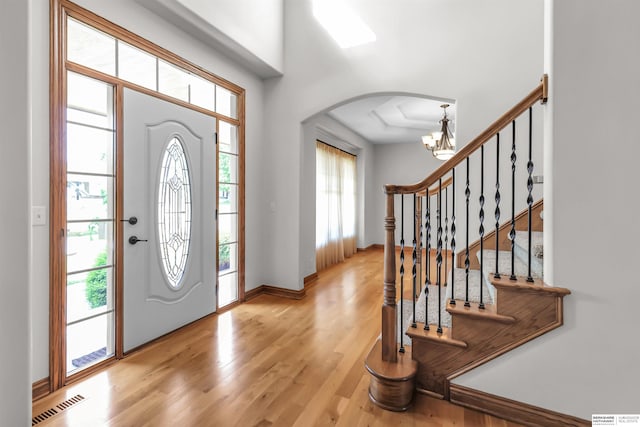 10149 Edward St, La Vista, NE 68128 - foyer featuring arched walkways, a chandelier, light wood-type flooring, and stairs