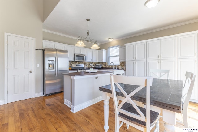 11351 S 198th St, Gretna, NE 68028 - kitchen with appliances with stainless steel finishes, white cabinets, a kitchen island, ornamental molding, and wood finished floors