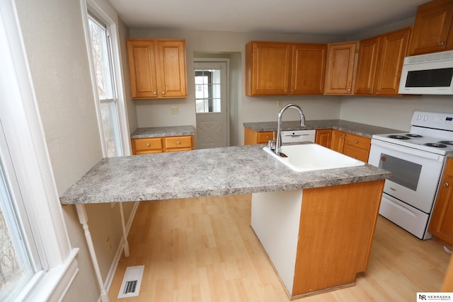 809 S 36th St, Omaha, NE 68105 - kitchen featuring white appliances, light wood finished floors, an island with sink, and brown cabinets