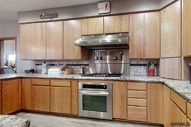 2035 355th Ave, Farragut, IA 51639 - kitchen featuring appliances with stainless steel finishes, under cabinet range hood, tasteful backsplash, light wood-type flooring, and light stone countertops