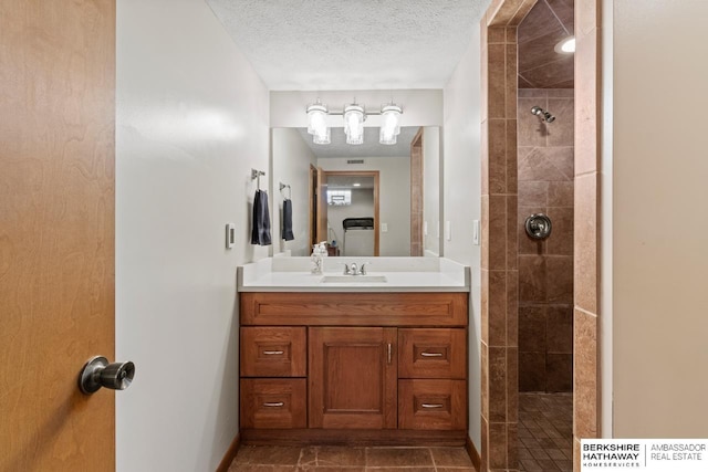 8832 Spaulding Cir, Omaha, NE 68134 - bathroom featuring a tile shower, vanity, a textured ceiling, and tile patterned floors