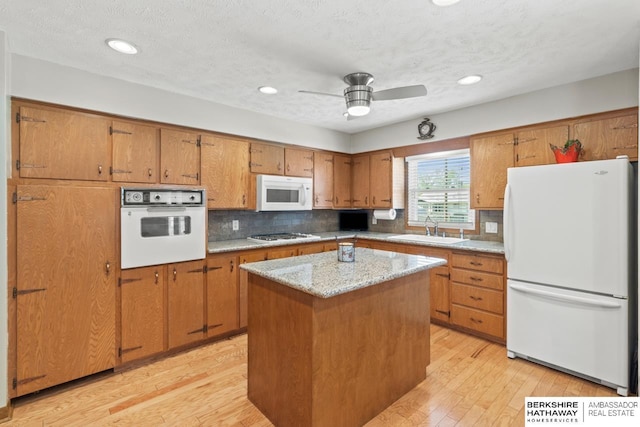 8832 Spaulding Cir, Omaha, NE 68134 - kitchen with white appliances, brown cabinetry, tasteful backsplash, light wood-style flooring, and recessed lighting