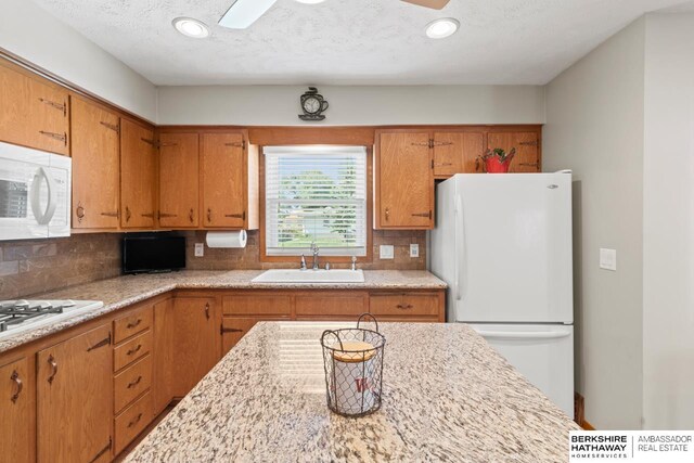 8832 Spaulding Cir, Omaha, NE 68134 - kitchen with white appliances, tasteful backsplash, brown cabinets, ceiling fan, and recessed lighting
