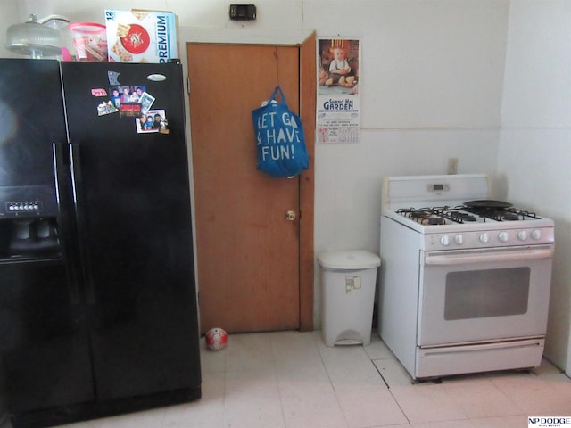 2711 Shirley St, Omaha, NE 68105 - kitchen featuring black refrigerator with ice dispenser, white gas range, and light tile patterned floors