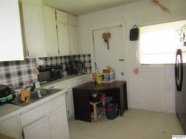 2711 Shirley St, Omaha, NE 68105 - kitchen featuring black microwave, light countertops, freestanding refrigerator, and white cabinetry