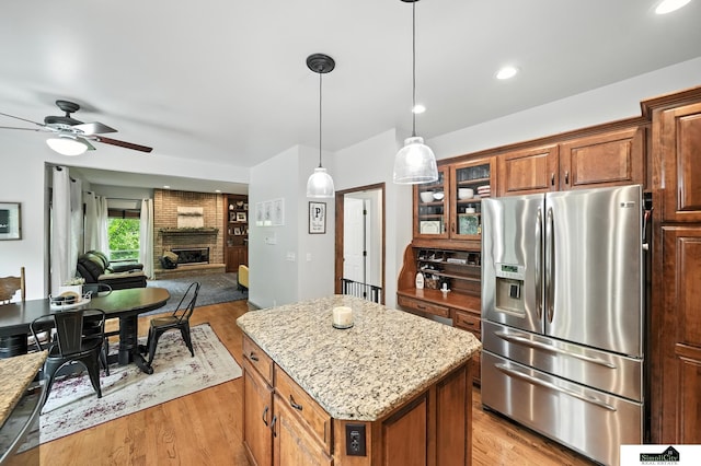 5807 S 167th Ave, Omaha, NE 68135 - kitchen with stainless steel fridge with ice dispenser, a brick fireplace, light wood-style floors, a ceiling fan, and a center island