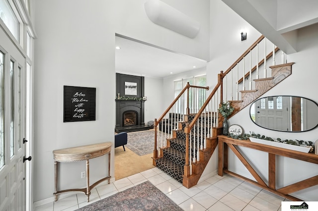 5807 S 167th Ave, Omaha, NE 68135 - foyer entrance with stairs, a fireplace with raised hearth, a towering ceiling, light tile patterned floors, and recessed lighting