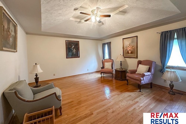 17315 M St, Omaha, NE 68135 - living area featuring a textured ceiling, light wood-style flooring, ceiling fan, and a tray ceiling