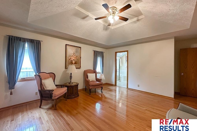 17315 M St, Omaha, NE 68135 - living area featuring a textured ceiling, a raised ceiling, light wood-style flooring, and ceiling fan