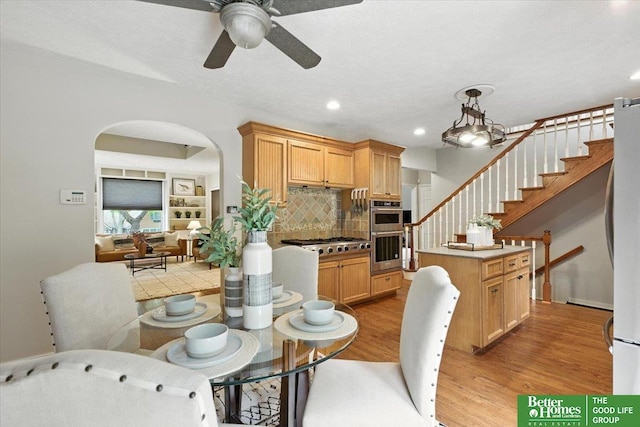 454 N 61st St, Omaha, NE 68132 - dining space featuring light wood-style flooring, ceiling fan, arched walkways, recessed lighting, and stairway