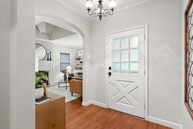 454 N 61st St, Omaha, NE 68132 - entrance foyer with arched walkways, ornamental molding, light wood-style flooring, a fireplace, and a chandelier