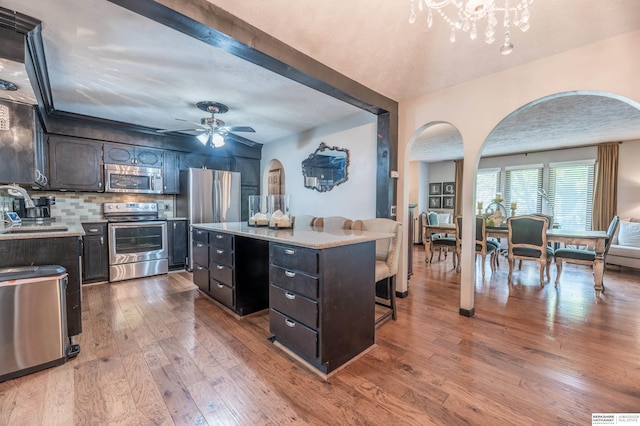2105 S 164th Ave, Omaha, NE 68130 - kitchen featuring stainless steel appliances, arched walkways, a kitchen island, wood-type flooring, and light countertops