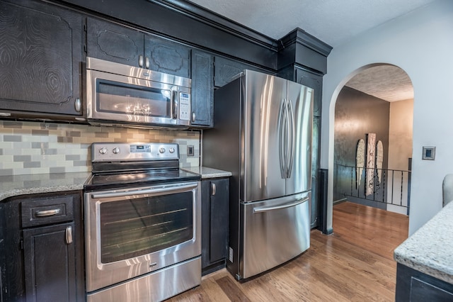 2105 S 164th Ave, Omaha, NE 68130 - kitchen with stainless steel appliances, arched walkways, light wood-style flooring, decorative backsplash, and a textured ceiling